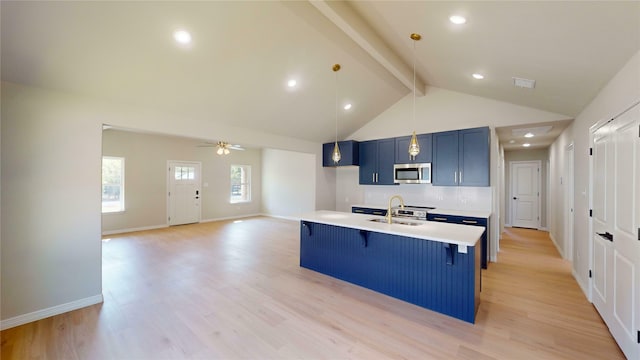 kitchen with a center island with sink, beam ceiling, sink, a kitchen breakfast bar, and light hardwood / wood-style flooring