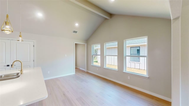 kitchen featuring beam ceiling, high vaulted ceiling, pendant lighting, sink, and light hardwood / wood-style flooring