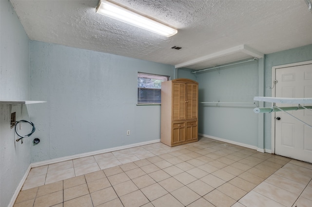 unfurnished room featuring a textured ceiling and light tile patterned floors