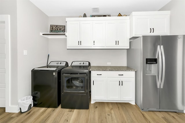 clothes washing area featuring cabinets, separate washer and dryer, and light wood-type flooring