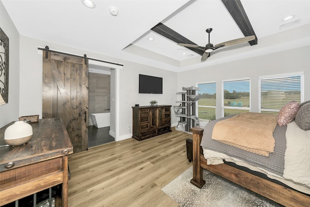 bedroom featuring light hardwood / wood-style floors, a raised ceiling, a barn door, and ceiling fan