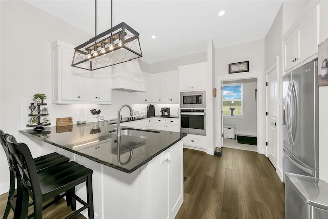 kitchen with white cabinetry, kitchen peninsula, appliances with stainless steel finishes, pendant lighting, and premium range hood