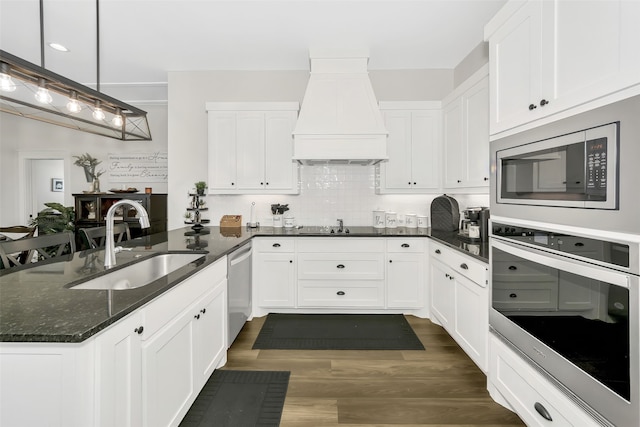 kitchen with dark hardwood / wood-style flooring, white cabinets, hanging light fixtures, custom range hood, and appliances with stainless steel finishes