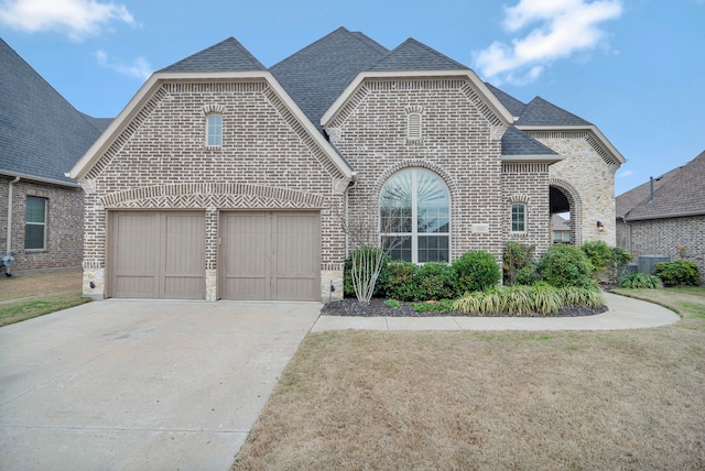 view of front of property with a garage, central AC, and a front yard