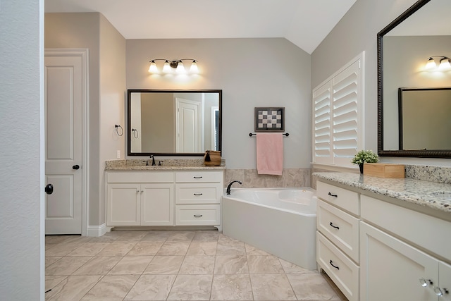 bathroom featuring vanity, a tub to relax in, and vaulted ceiling