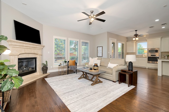 living room featuring a wealth of natural light, ceiling fan, and dark hardwood / wood-style flooring