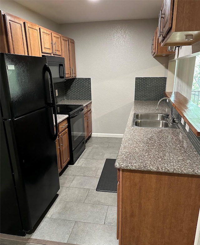 kitchen with dark stone countertops, decorative backsplash, sink, and black appliances