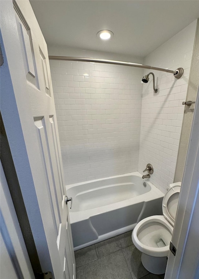 bathroom featuring tile patterned flooring, tiled shower / bath combo, and toilet