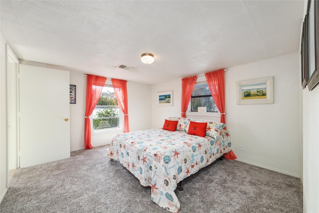 bedroom with a textured ceiling and dark carpet