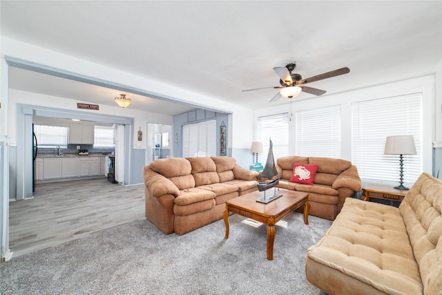 living room with ceiling fan, sink, a wealth of natural light, and light hardwood / wood-style flooring