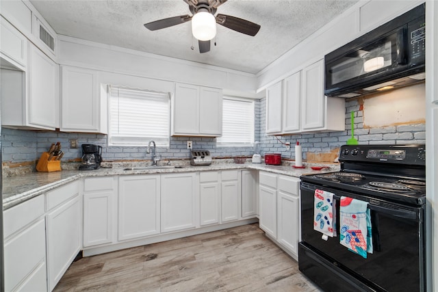 kitchen featuring a healthy amount of sunlight, sink, white cabinets, and black appliances