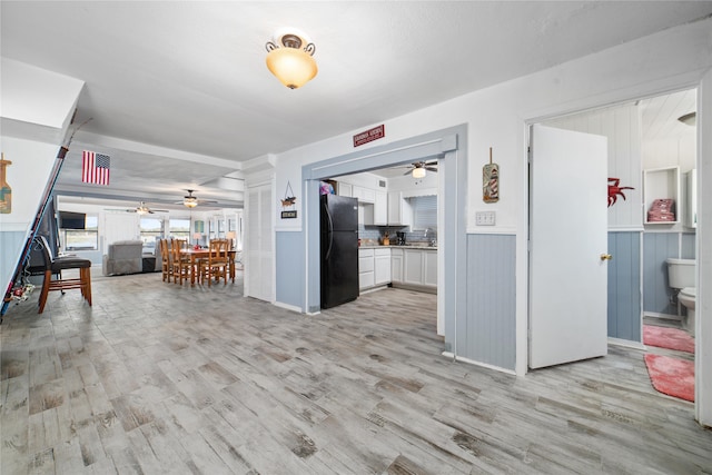 kitchen with black fridge, light hardwood / wood-style flooring, and white cabinets