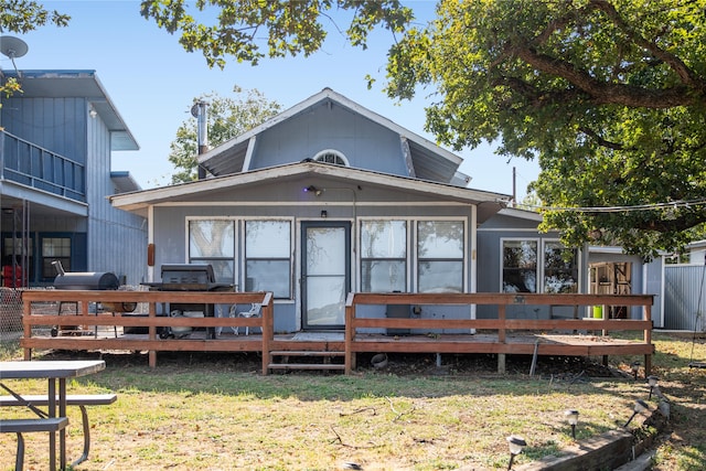 rear view of house featuring a wooden deck and a lawn