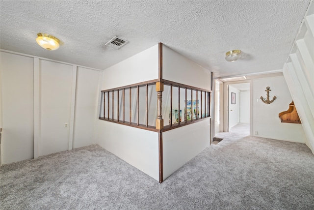 hallway featuring light carpet and a textured ceiling