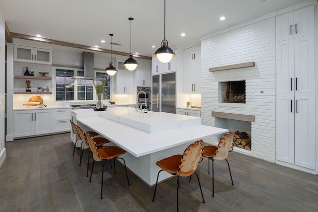 kitchen with a breakfast bar area, a large island, pendant lighting, a fireplace, and appliances with stainless steel finishes