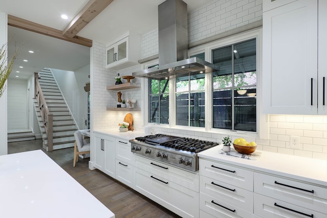 kitchen featuring island range hood, white cabinetry, decorative backsplash, stainless steel gas stovetop, and dark wood-type flooring