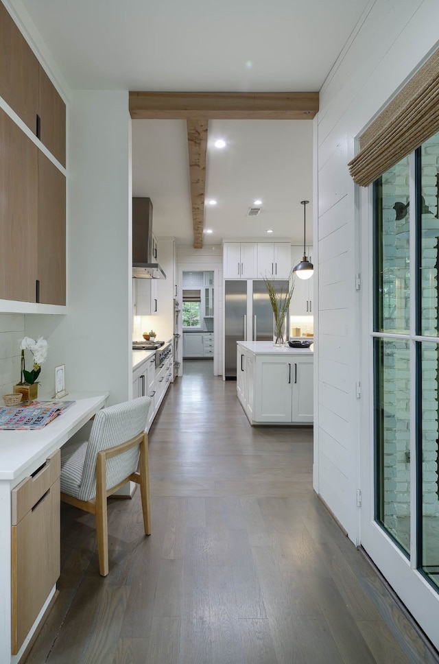 kitchen featuring dark wood-type flooring, white cabinetry, beamed ceiling, and decorative light fixtures