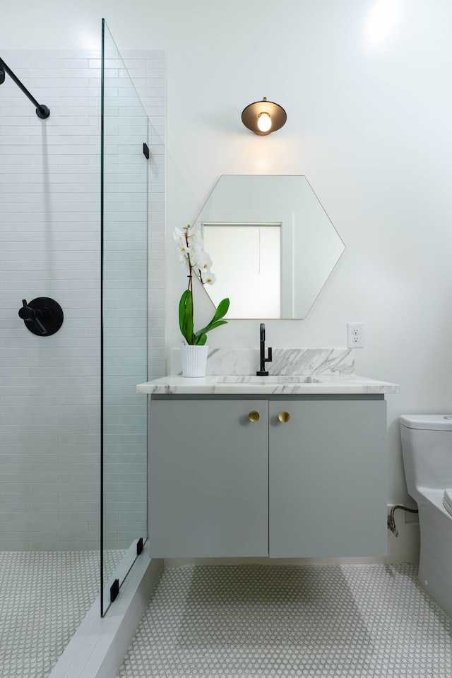 bathroom featuring toilet, tile patterned floors, vanity, and a shower with door