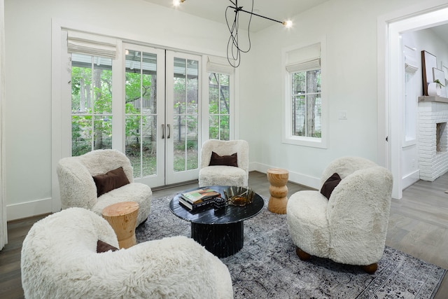 living area with a brick fireplace, hardwood / wood-style flooring, plenty of natural light, and french doors