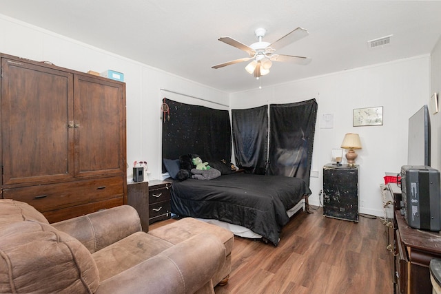 bedroom with dark hardwood / wood-style flooring, crown molding, and ceiling fan