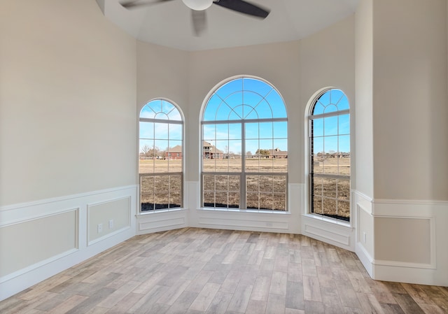 unfurnished room featuring a wealth of natural light, ceiling fan, and light hardwood / wood-style floors