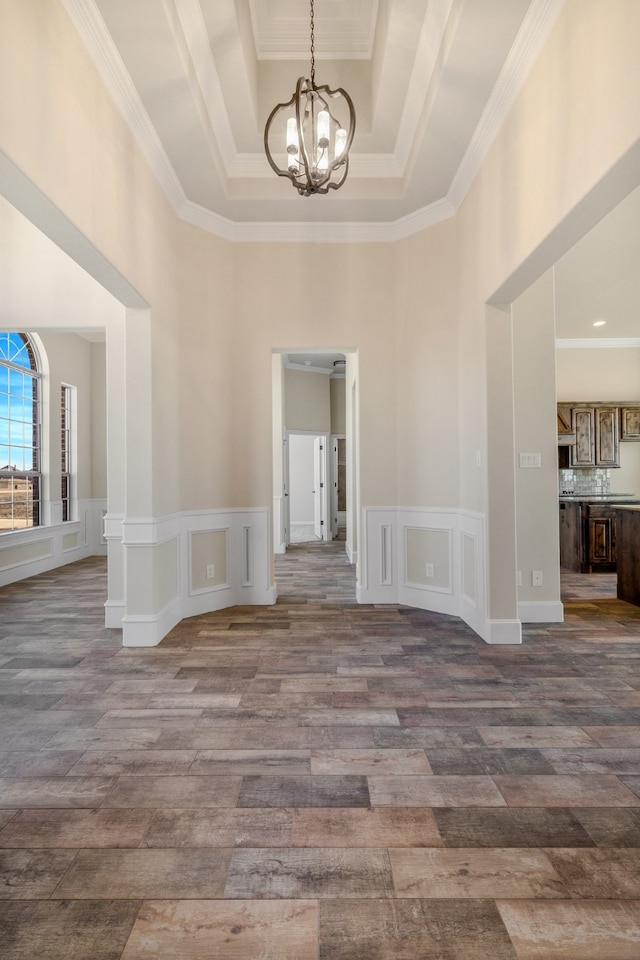 empty room featuring light hardwood / wood-style floors, an inviting chandelier, ornamental molding, and a raised ceiling