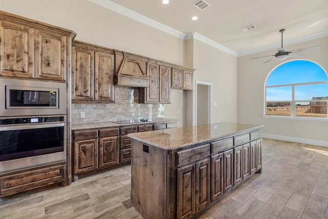 kitchen featuring ornamental molding, stainless steel appliances, custom exhaust hood, and light hardwood / wood-style flooring