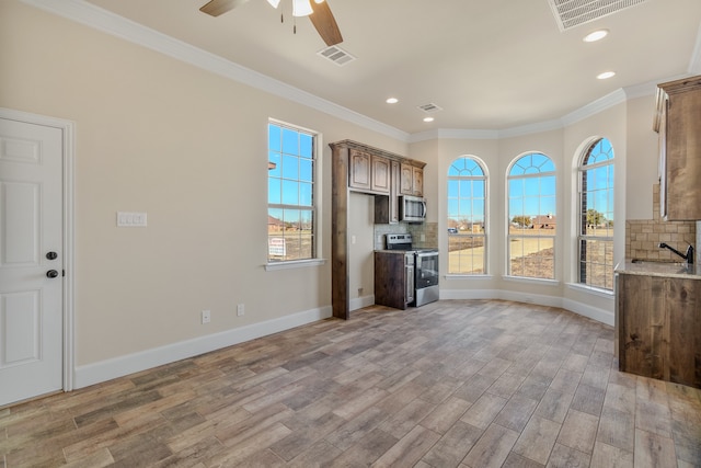 kitchen featuring ceiling fan, wood-type flooring, backsplash, and appliances with stainless steel finishes