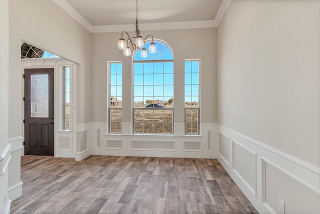 entryway with light wood-type flooring, a notable chandelier, and crown molding