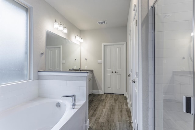 bathroom with hardwood / wood-style flooring, vanity, and plus walk in shower