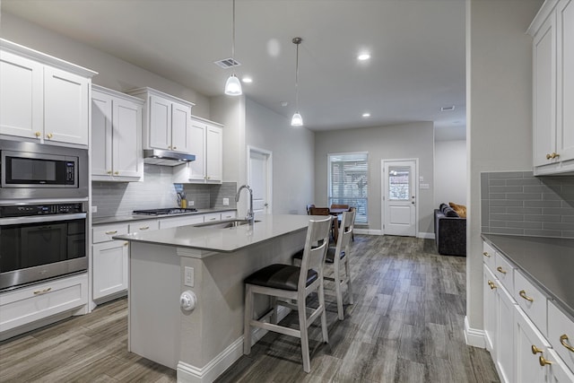 kitchen featuring hardwood / wood-style flooring, white cabinetry, sink, appliances with stainless steel finishes, and decorative light fixtures