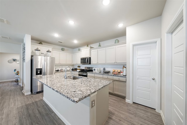 kitchen featuring a center island with sink, appliances with stainless steel finishes, sink, hardwood / wood-style flooring, and white cabinets