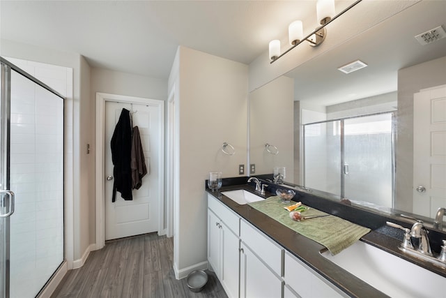 bathroom featuring hardwood / wood-style flooring, a shower with shower door, and vanity