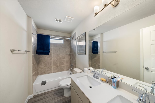 full bathroom with toilet, tiled shower / bath combo, vanity, and hardwood / wood-style floors