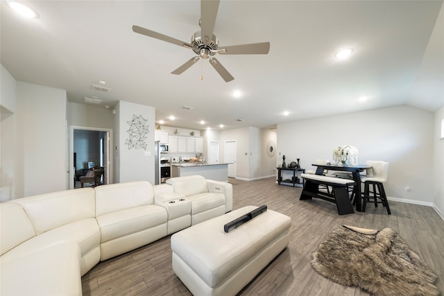 living room with light hardwood / wood-style flooring, ceiling fan, and vaulted ceiling