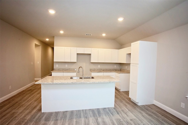 kitchen featuring light hardwood / wood-style floors, a center island with sink, sink, and light stone counters