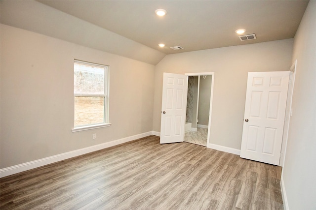 unfurnished bedroom featuring light wood-type flooring and vaulted ceiling