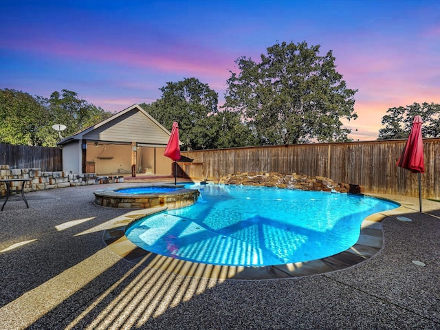 pool at dusk featuring an in ground hot tub and a patio area