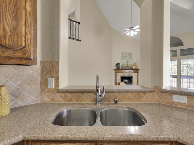 kitchen featuring light stone countertops, sink, decorative backsplash, and lofted ceiling