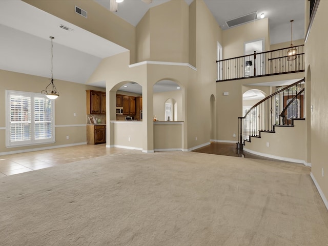 unfurnished living room featuring light colored carpet, a chandelier, and high vaulted ceiling