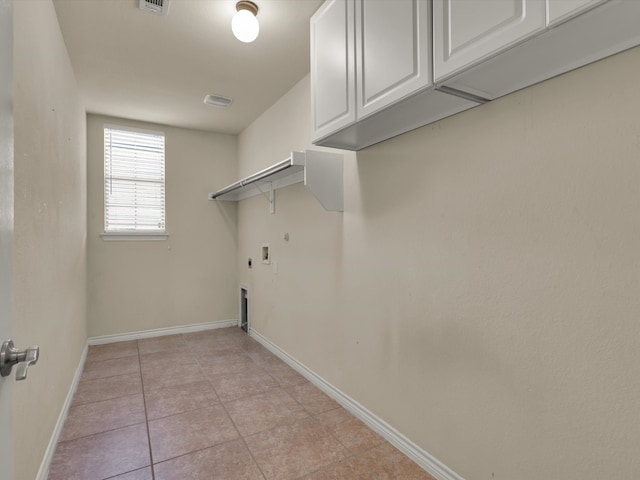 clothes washing area featuring gas dryer hookup, hookup for an electric dryer, washer hookup, light tile patterned floors, and cabinets