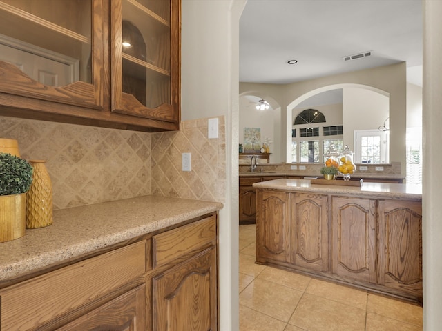 kitchen featuring tasteful backsplash, light stone counters, sink, and light tile patterned floors