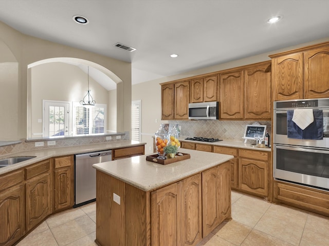 kitchen with a kitchen island, hanging light fixtures, light tile patterned floors, and stainless steel appliances