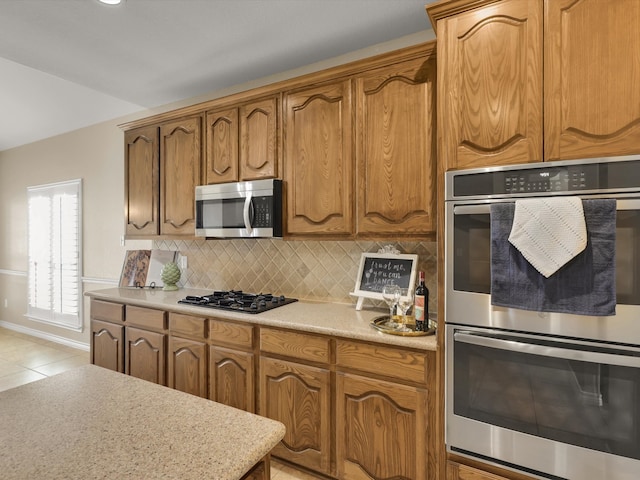 kitchen with stainless steel appliances, light tile patterned floors, and tasteful backsplash