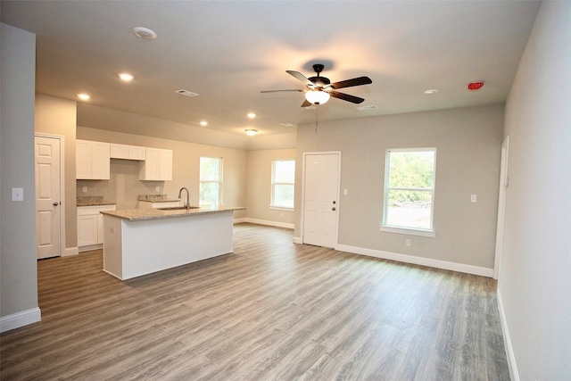 kitchen featuring light wood-type flooring, sink, an island with sink, white cabinets, and ceiling fan