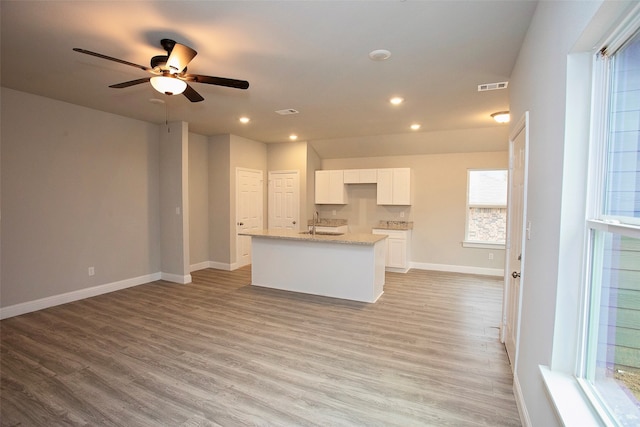 kitchen featuring ceiling fan, white cabinetry, a kitchen island with sink, and light hardwood / wood-style flooring