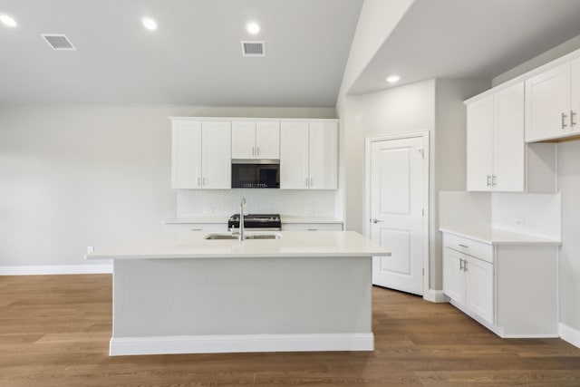 kitchen with dark hardwood / wood-style floors, white cabinetry, backsplash, and a center island with sink