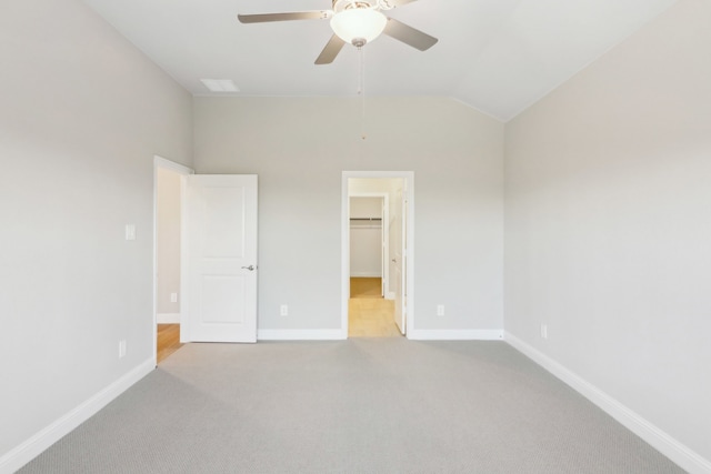 unfurnished bedroom featuring ceiling fan, light colored carpet, a spacious closet, and lofted ceiling