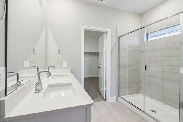 bathroom featuring a shower with shower door and vanity