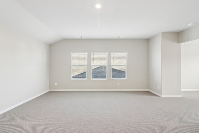 carpeted spare room with vaulted ceiling